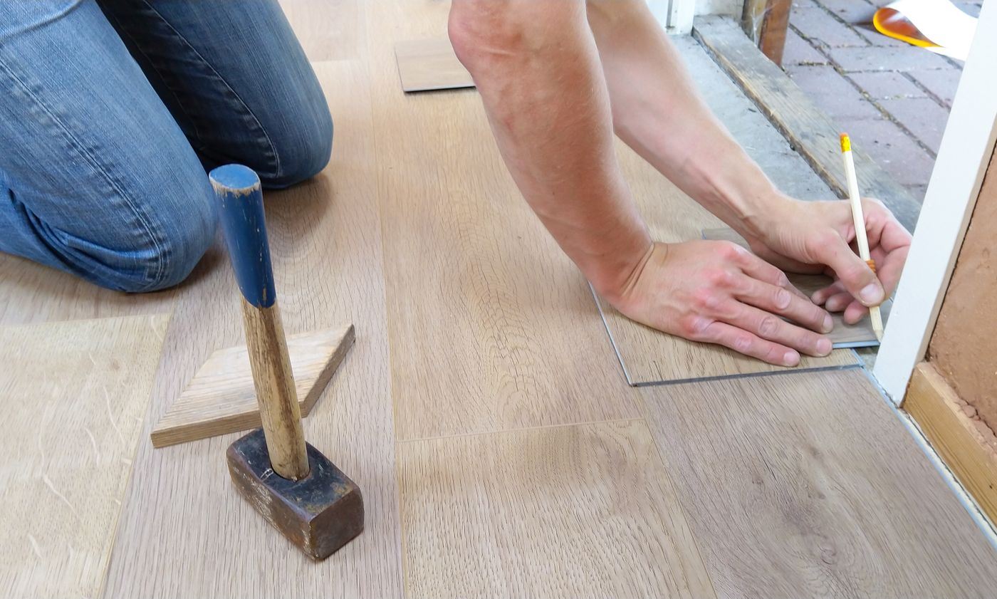 Flooring installer measuring a plank carefully
